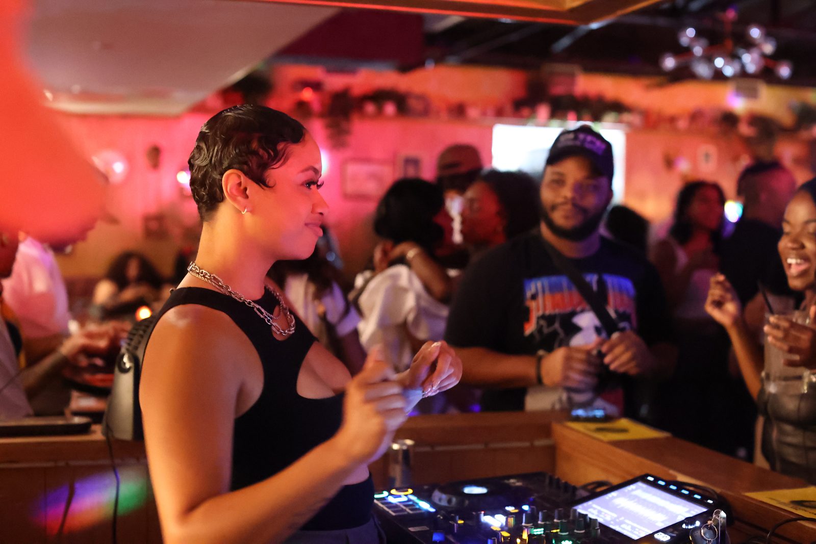 Bri Marie smiling behind the decks as the crowd dances under red lights